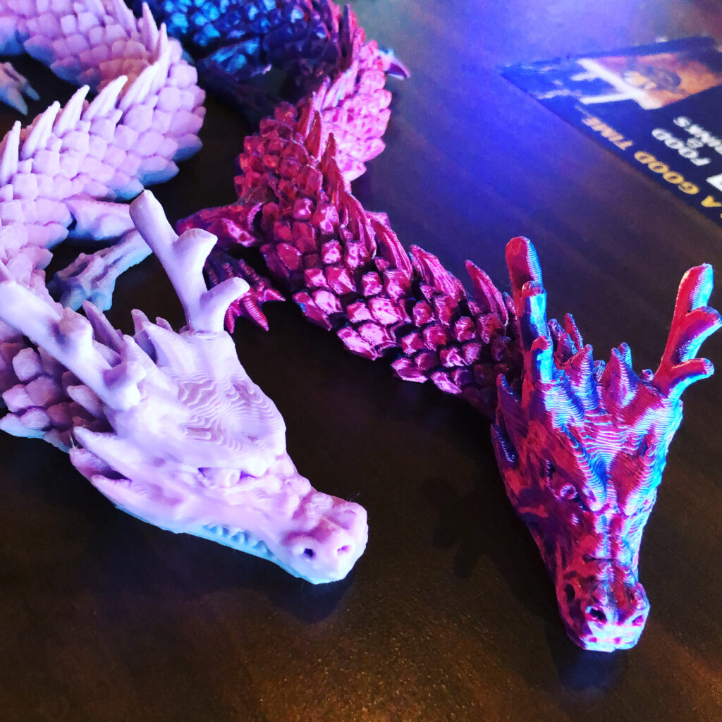 Two three-D printed dragon heads laying on a table